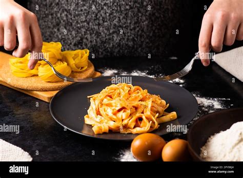 A close-up of hands holding a fork, digging into a plate of fast food