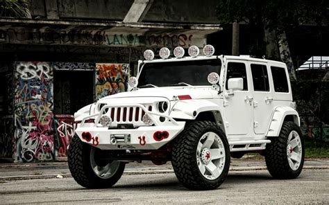 A White Jeep Parked In Front Of A Graffiti Covered Building