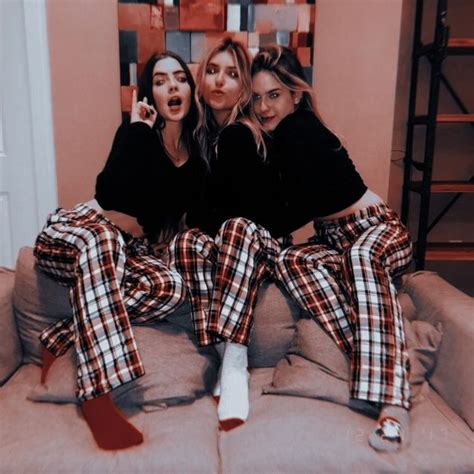 Three Women Sitting On Top Of A Couch Wearing Matching Plaid Pajamas