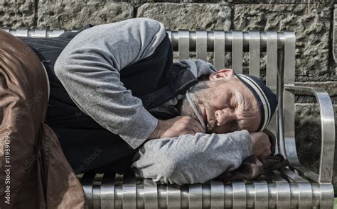 Homeless Man Sleeping With Old Blankets On A Park Bench Stock Photo