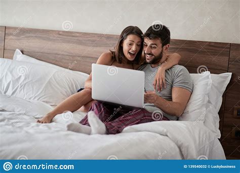 Happy Couple Lying On A Bed With Computer Beautiful Married Couple