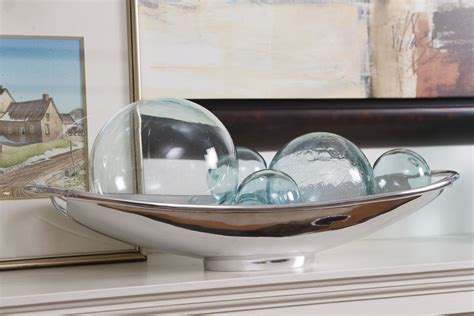A Bowl Filled With Glass Balls Sitting On Top Of A White Dresser Next