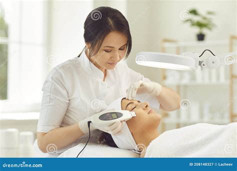 Smiling Dermatologist Making Ultrasound Apparatus Facial Cleaning For Young Woman Stock Image