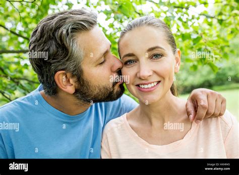 Man Kissing Woman With Love As A Happy Couple In Summer In The Nature
