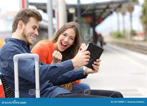 Euphoric Couple Playing Games In A Tablet In A Train Station Stock