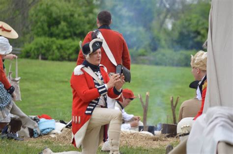 People Dressed In Colonial Clothing Sitting On The Grass