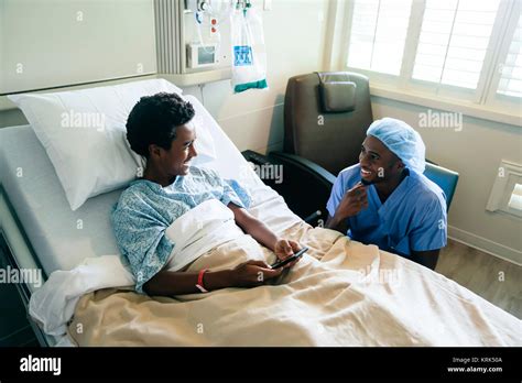 Black Nurse Talking To Boy In Hospital Bed Stock Photo Alamy
