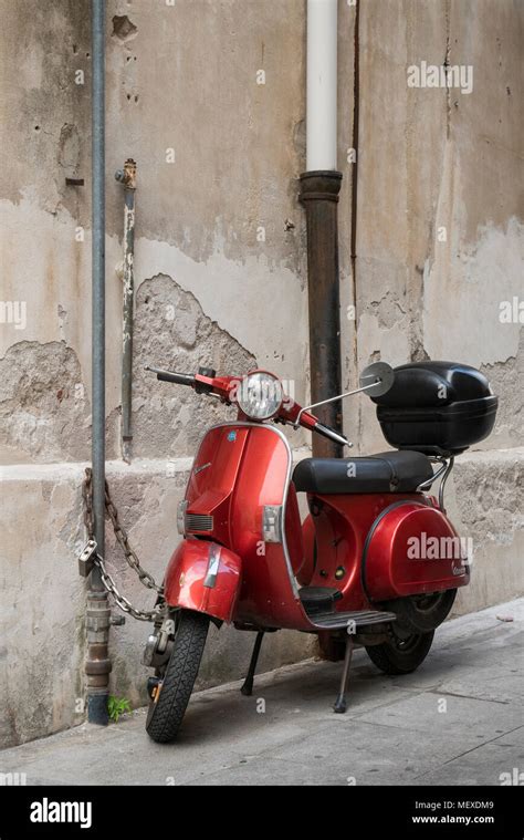 An Old Red Vespa Scooter With Top Box Parked On A Street In Palermo