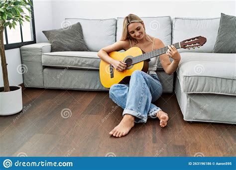 Young Blonde Woman Smiling Confident Playing Classical Guitar At Home