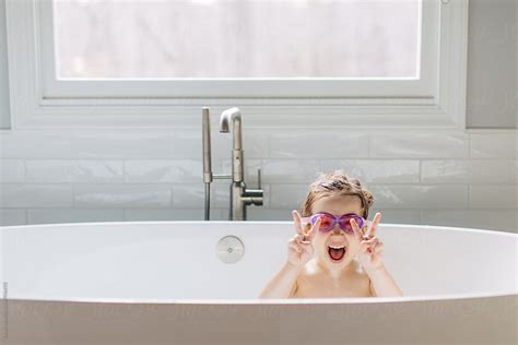 Cute Young Girl With Swim Goggles Making The Victory Sign In A Bathtub