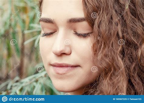 Portrait Of Girl With Brown Curly Hair On Background Of Green Bush Sea