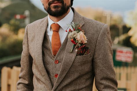 Autumn groom outfit with rust orange tie and tweed waistcoat and jacket