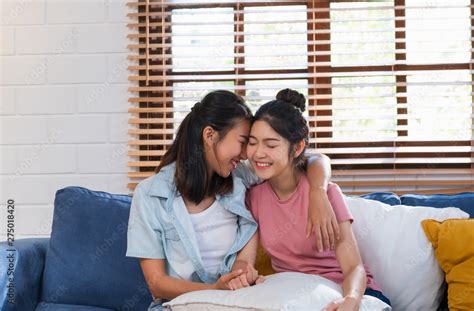 Happy Asian Lesbian Couple Hug Each Other With Love On Sofa At Living