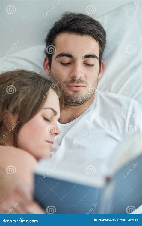 Enjoy The Bliss Of Homeliness A Young Couple Reading A Book In Bed