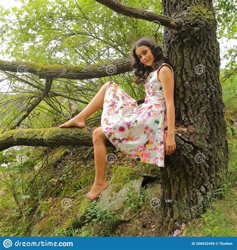 Teenage Girl In Summer Sitting On Branch Of An Old Tree Stock Photo