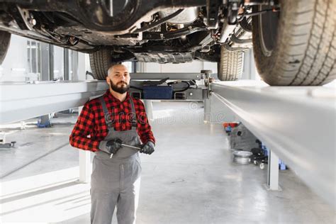 Auto Mechanic Working Underneath A Lifted Car Auto Mechanic Working In