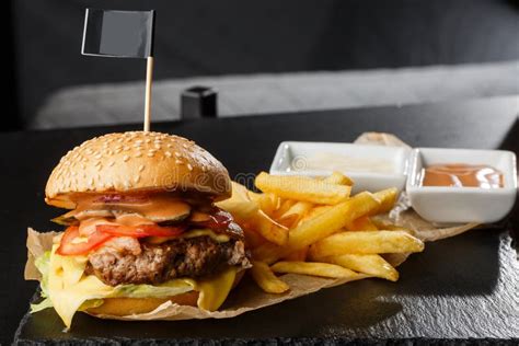 Big Single Cheeseburger With French Fries Isolated On Black Background