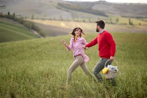 A Young Happy Couple Enjoying The Nature And A Large Meadow While