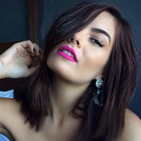 A Woman With Long Dark Hair And Pink Lipstick On Her Lips Is Posing For