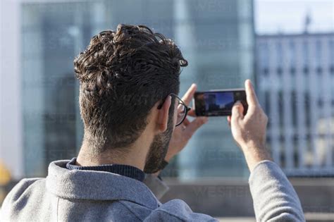 Back View Of Man Taking Picture With Smartphone Stock Photo