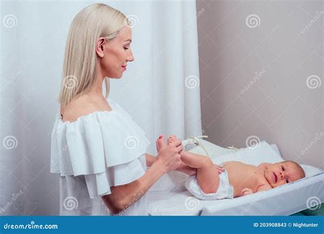 Caucasian Mother Applying Baby Powder Before Putting Diapers On Her Four Month Old Baby In Bed