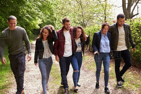 Six Young Adult Friends Walking Together In A Country Lane Stock