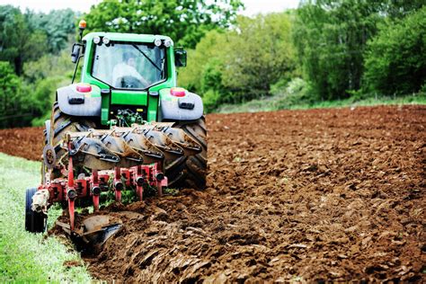 A Tractor Ploughing The Soil In A Field Harrowing Stock Photo