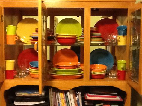 A Wooden Cabinet Filled With Lots Of Colorful Dishes