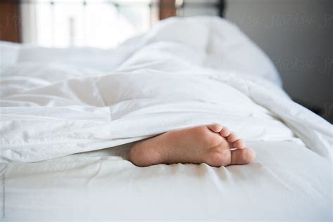 Feet Stick Out Of White Bed Covers By Cara Dolan