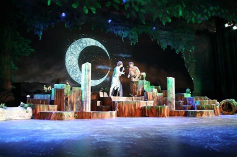 Two People On Stage Performing In Front Of A Large Moon And Crescent