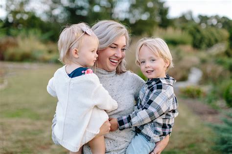 beautiful mother holding her son and daughter in her arms by stocksy contributor jakob