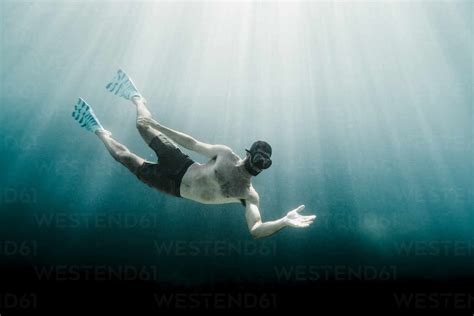 Full Length Of Man Swimming Underwater In The Ocean Facing Camera Stock