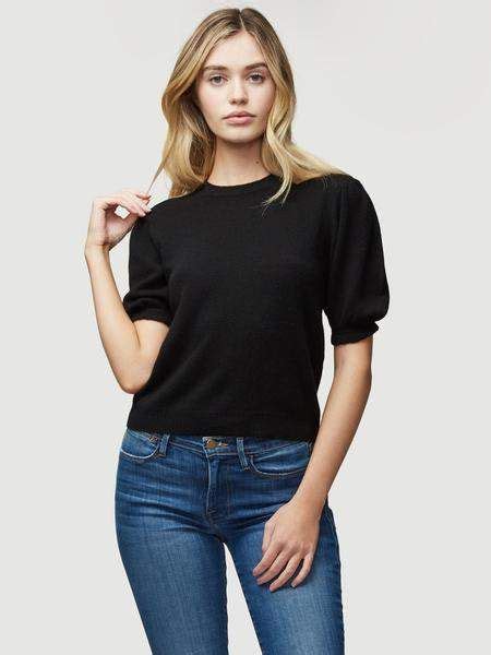 A Woman In Black Shirt And Jeans Posing For The Camera With Her Hand On
