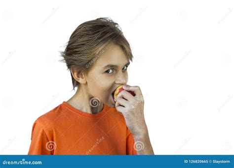 Muchacho Joven En Camiseta Anaranjada Que Come Una Manzana Roja Imagen