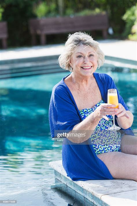 Senior Woman Sitting On Pool Deck With Drink High Res Stock Photo