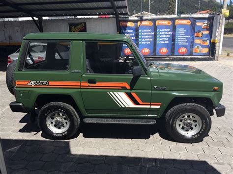 A Green Jeep With Orange And White Stripes Parked In Front Of A Building