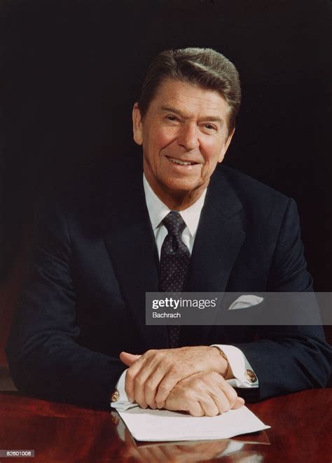 Portrait Of American President Ronald Reagan As He Sits At A Table In