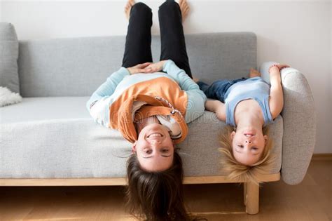 Child Hanging Upside Down From A Couch At Home Smiling Happily Stock