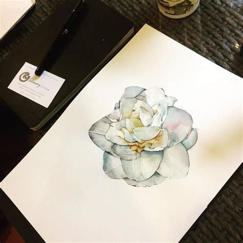 A Watercolor Painting Of A White Flower On Paper Next To A Pen And Ink