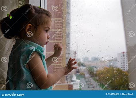 Beautiful Little Girl Looking Out The Window In The Rain Stock Image