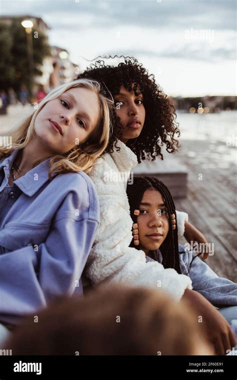 Portrait Of Female Friends Sitting On Pier Stock Photo Alamy