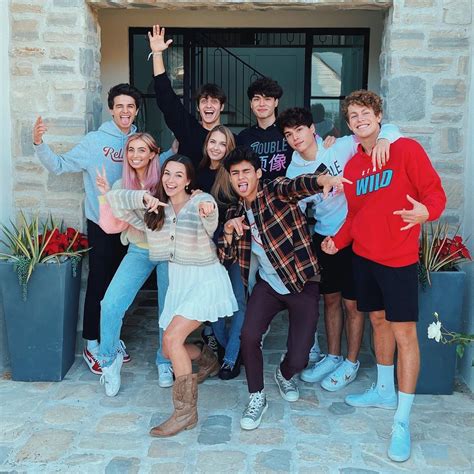 A Group Of People Posing For A Photo In Front Of A Door With Their Hands Up