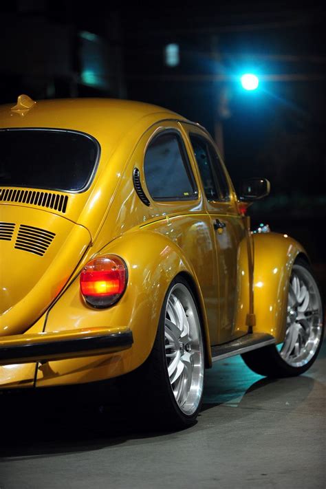 A Yellow Vw Bug Parked On The Street At Night