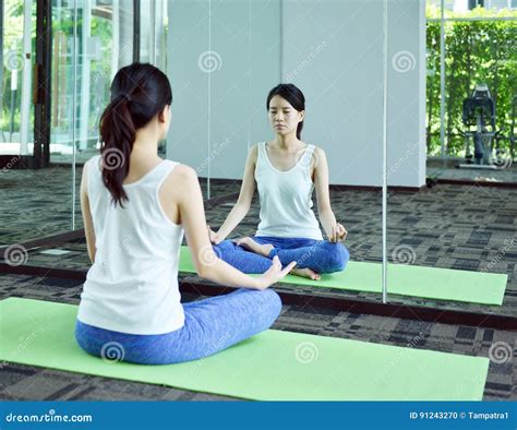 Молодая женщина размышляя перед зеркалом в комнате йоги жулик йоги Стоковое Фото изображение