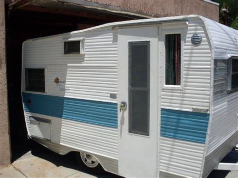 A White And Blue Trailer Parked In Front Of A Building With A Garage