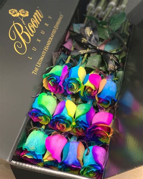 A Box Filled With Rainbow Colored Roses Sitting On Top Of A Table