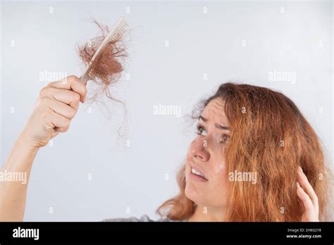 Caucasian woman with a grimace of horror holds a comb with a bun of