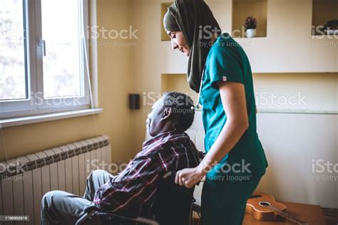 Senior Man In A Wheelchair Talking To His Home Caregiver Arabian
