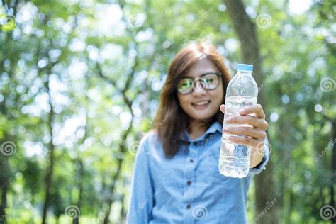 Young Woman Drinking Water From Bottle In Green Garden Park Asian