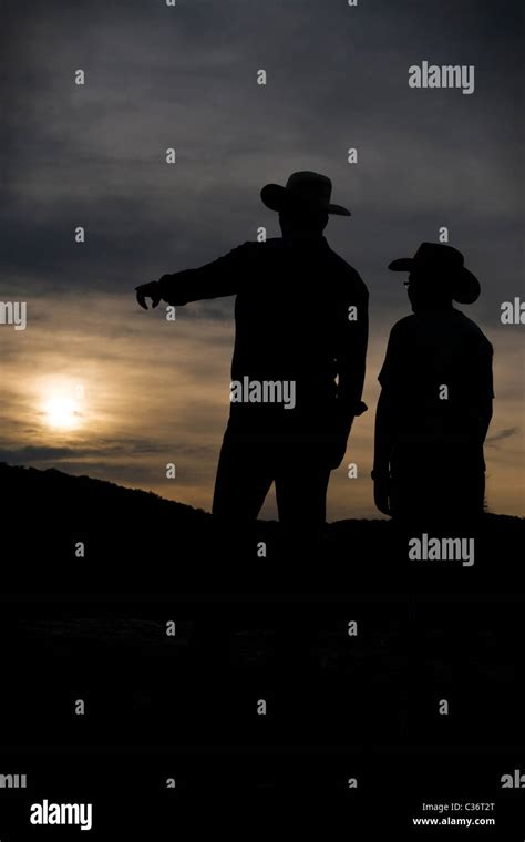 Cowboy Father Is Proudly Showing The Land To His Son At Sunset Stock